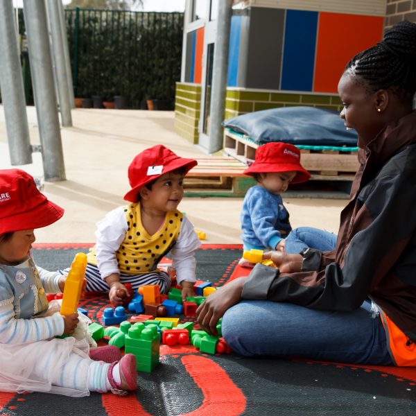 an educator playing with 3 toddlers