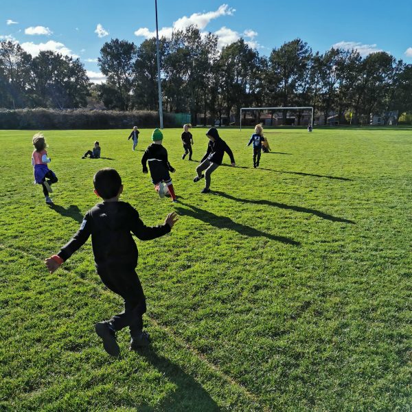 preschoolers playing soccer on oval