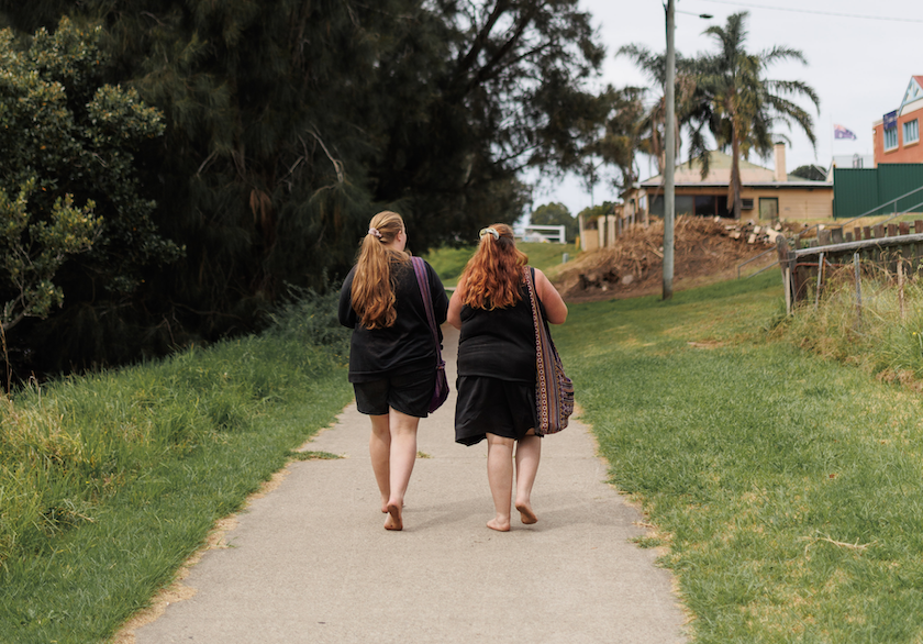 Mother and daughter walking away on footpath