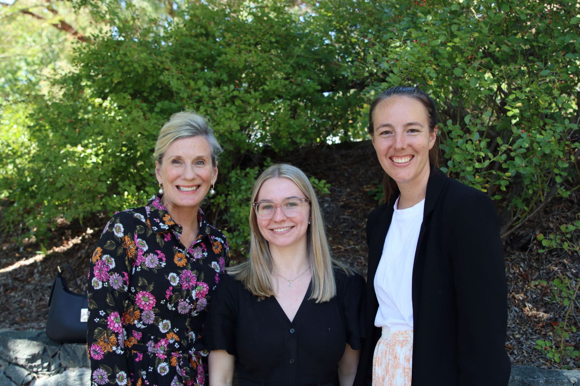 Three Anglicare staff members outside in front of a green leafy background after the 2026 Anglicare Easter Service