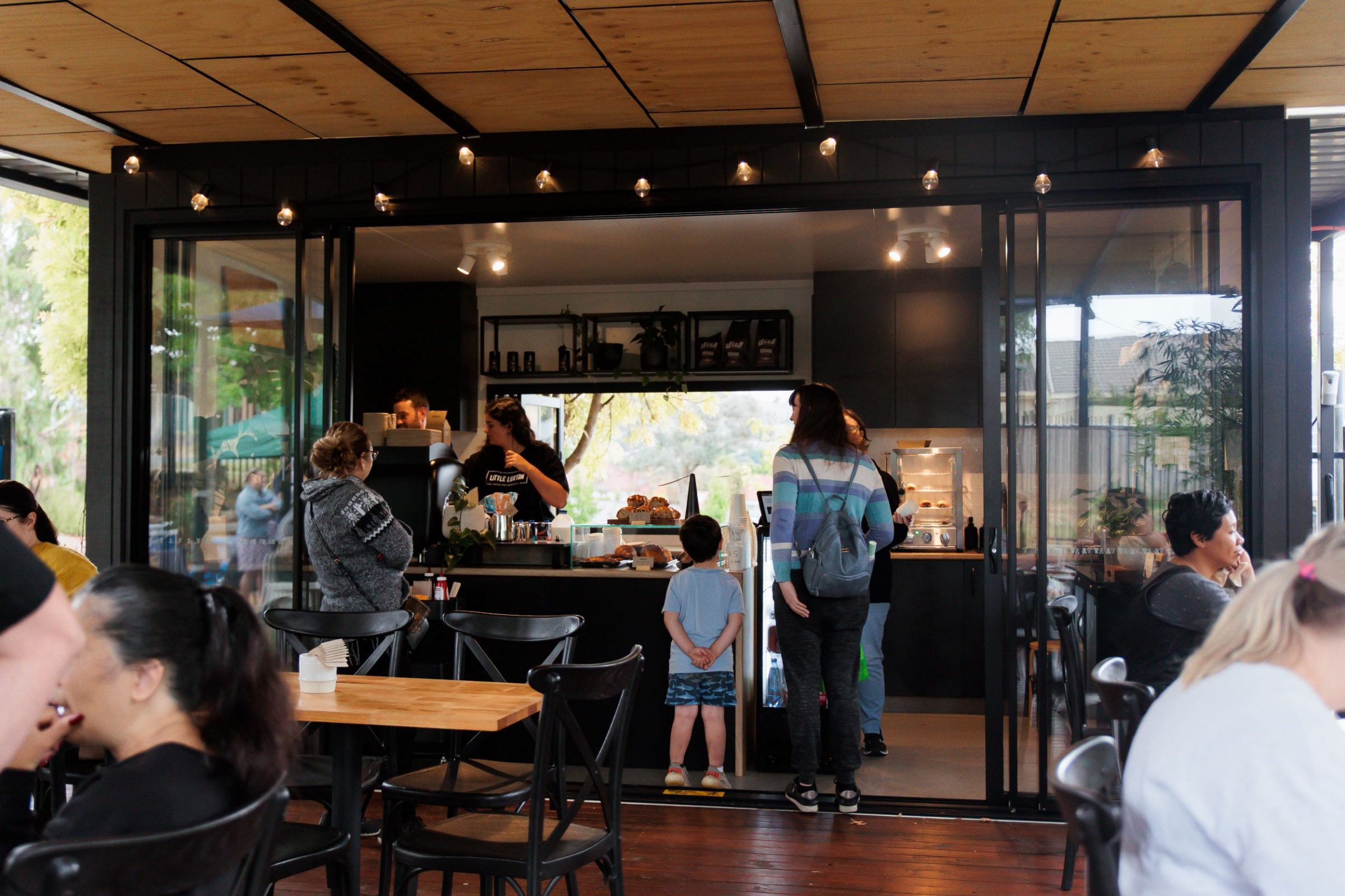People sitting in cafe chairs and waiting in line for coffee at social enterprise cafe, Little Luxton