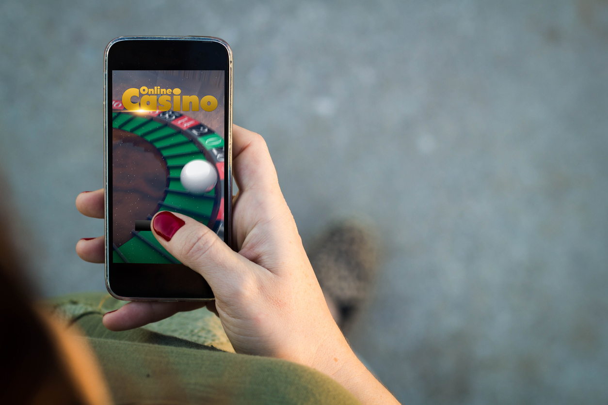 Female hand holding a phone open to an online gambling website.