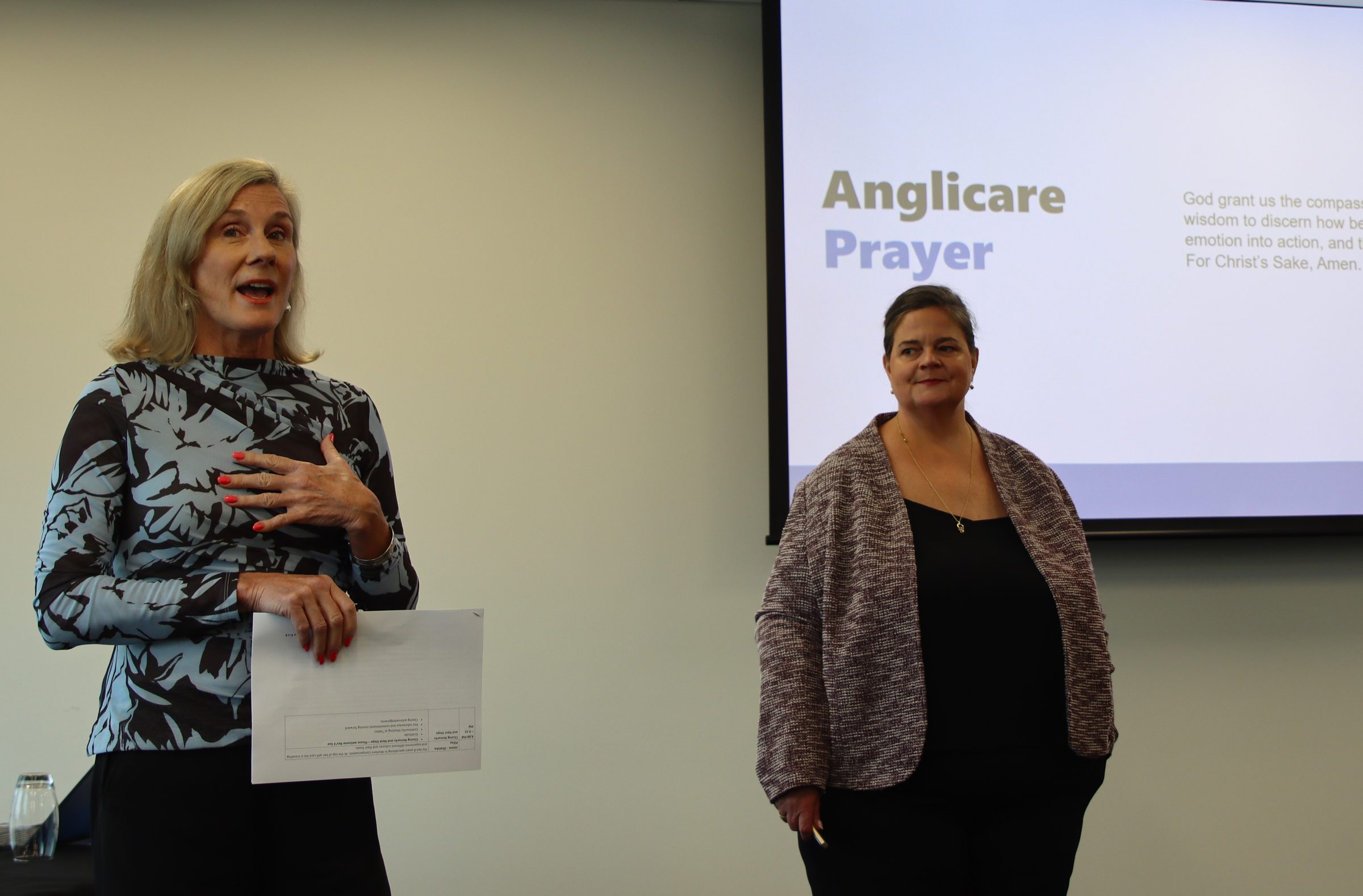 Two Anglicare staff members reading the Anglicare Prayer