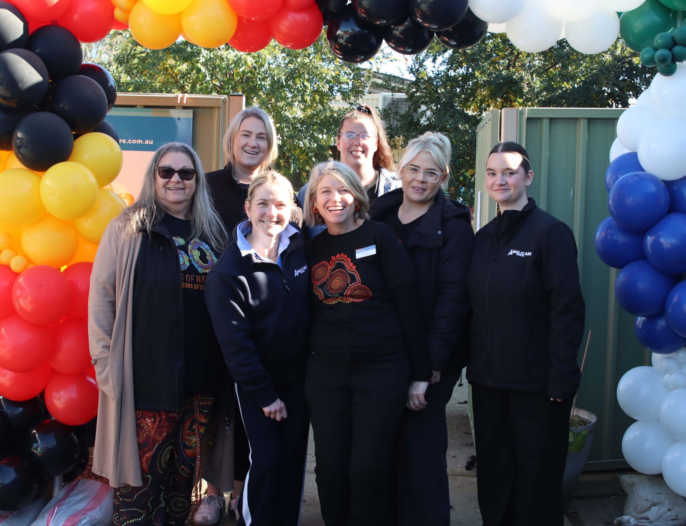 Staff members from Anglicare's Ashmont Community Resource Centre under indigenous coloured balloons